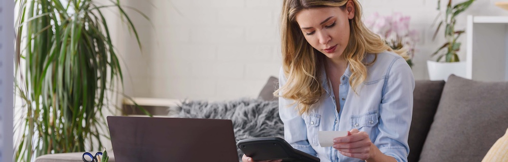 young beautiful woman working on a computer at home calculating monthly expenses doing home budgeting