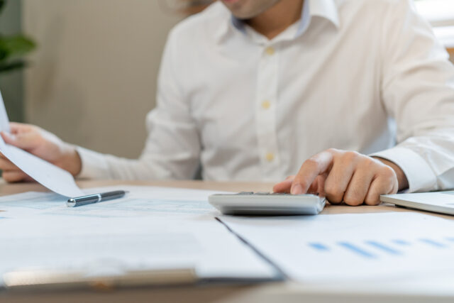 Close up hand of stress asian young employee business man, male calculate tax income and expenses, bills, credit card for payment or payday on table at home office. Financial, finance people concept.