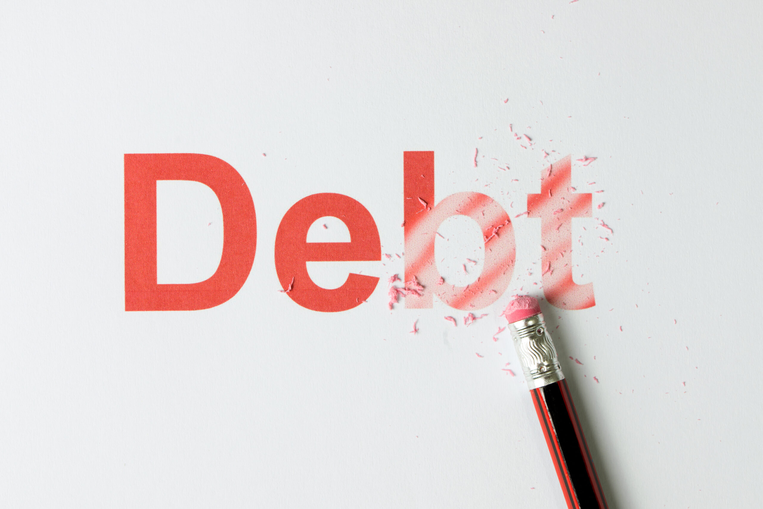 Close up of red pencil erasing the word debt on paper