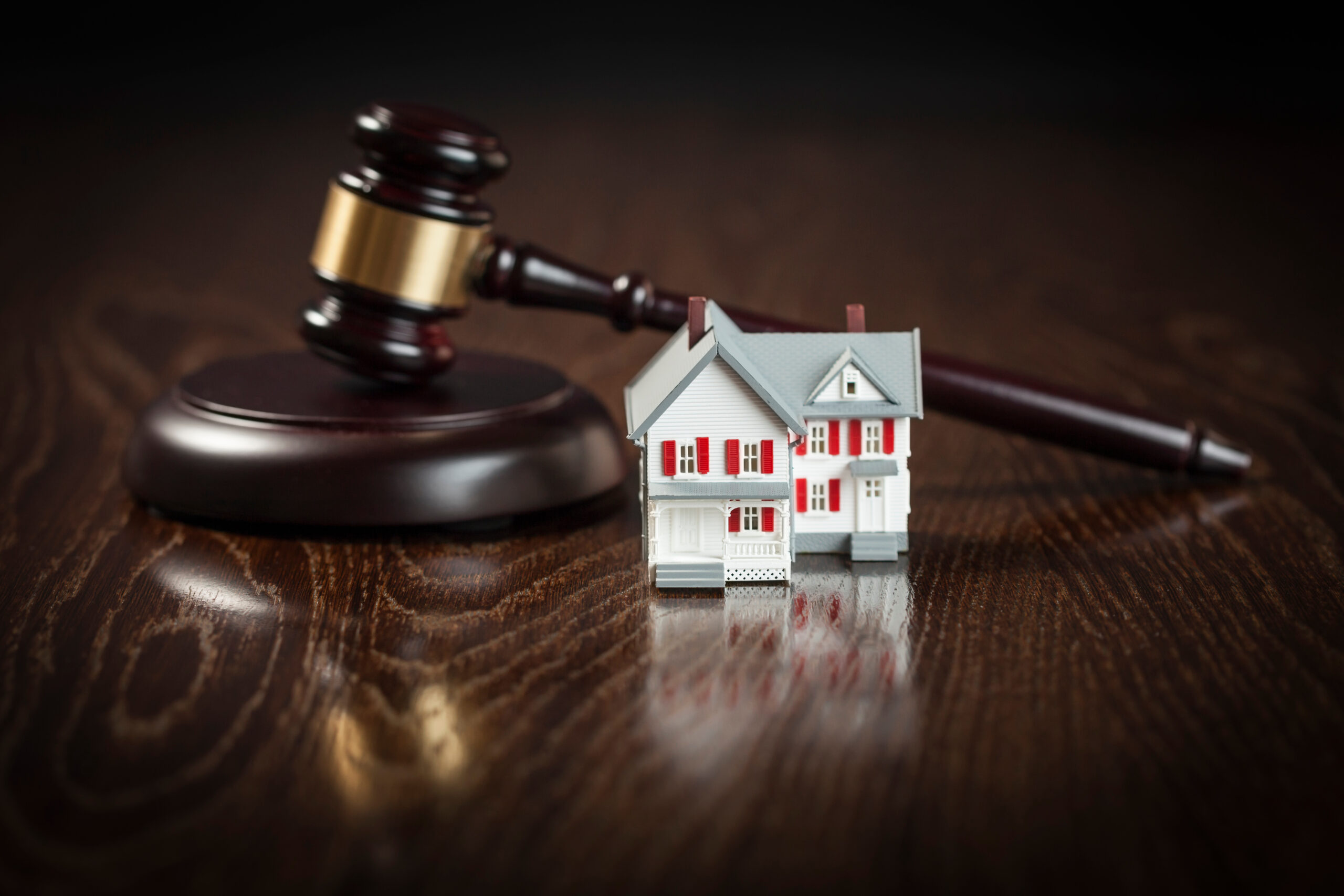 Gavel and Small Model House on Wooden Table.