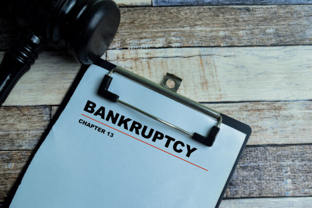 Concept of Bankruptcy Chapter 13 write on paperwork with gavel isolated on wooden background.