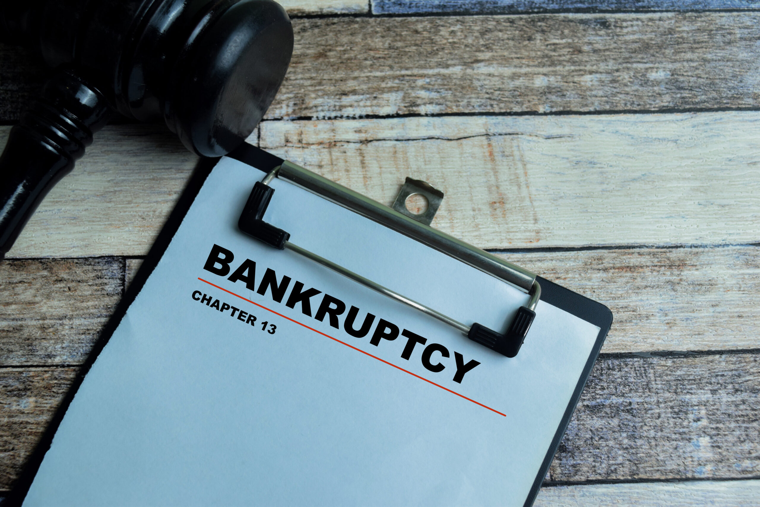 Concept of Bankruptcy Chapter 13 write on paperwork with gavel isolated on wooden background.