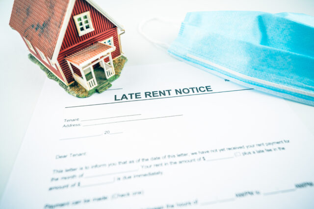 Late rent notification letter with model house and facial mask.