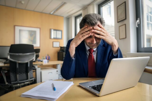 Tired businessman in the office stressed about debt on computer